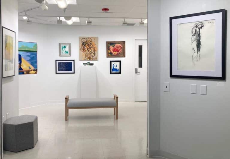 An art gallery with an assortment of artworks including prints, a guilt, paintings and pottery.