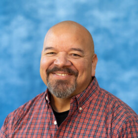 Dwayne Oothoudt headshot on blue background.